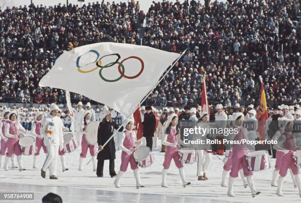 View of drummers marching with the Olympic Flag bearer as participating teams line up behind during the opening ceremony of the 1972 Winter Olympics...