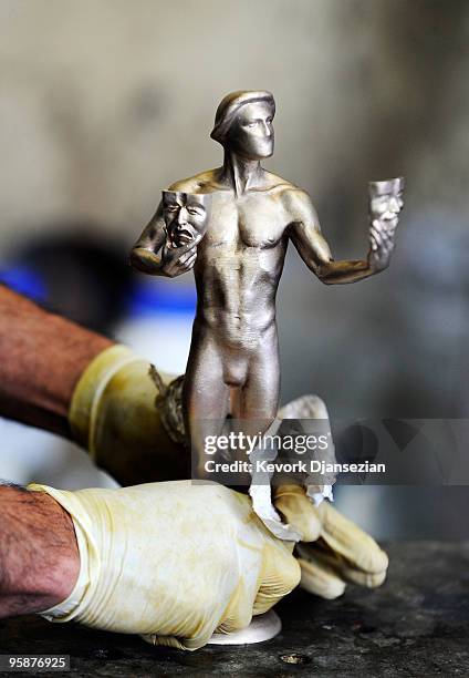Worker cleans "The Actor" statuette before applying the the green-black patina at the American Fine Arts Foundry on January 19, 2010 in Burbank,...