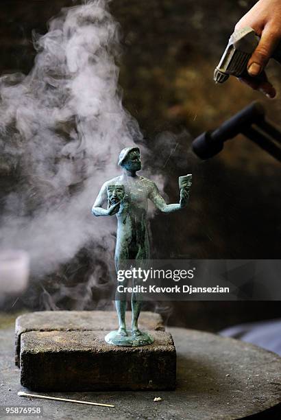 Smoke rises after a worker applies the green-black patina to an "The Actor" statuette at the American Fine Arts Foundry on January 19, 2010 in...