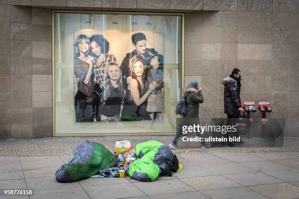 Deutschland Germany Berlin Zwei Obdachlose liegen vor einer Kaufhauswerbung auf dem Alexanderplatz. Zwei Passanten beim Vorbeigehen halten sich die...