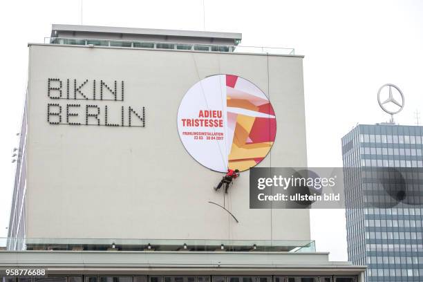 Deutschland Germany Berlin Ein Arbeiter entfernt die Aussenwerbung für eine Frühlingsinstallation im Bikini-Haus.