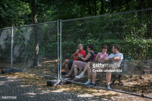 Deutschland Germany Berlin Touristen sitzen auf einer Bank im Durchgang zwischen Brandenburger Tor und Reichstag. Ein Absperrzaun, der bei...