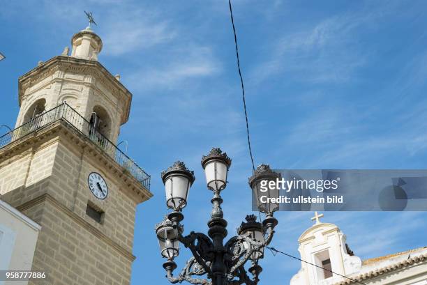 Typische historische Strassenlaterne vor Kirchturm und blauem Himmel in Cadiz