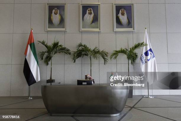 An employee sits beneath photographs of Sheikh Khalifa bin Zayed Al Nahyan, United Arab Emirates' president and ruler of Abu Dhabi, left, Sheikh...