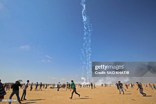 Palestinian protesters flee from falling tear gas cannisters dropped by an Israeli quadcopter drone during clashes near the border with Israel east...