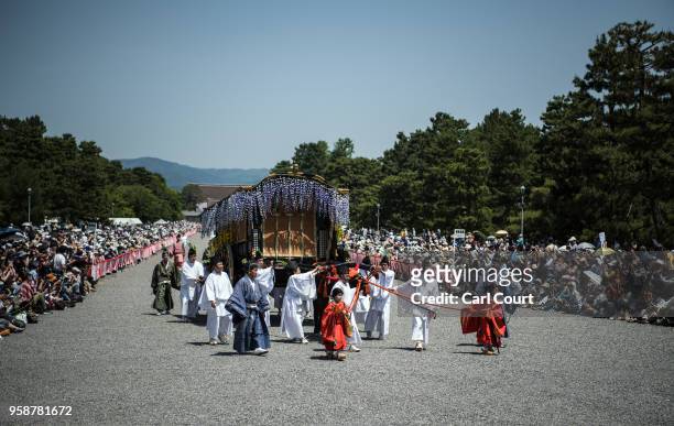 Participants in Heian period dress pull an ox cart as they parade through the grounds of Kyoto Imperial Palace during the Aoi Festival on May 15,...