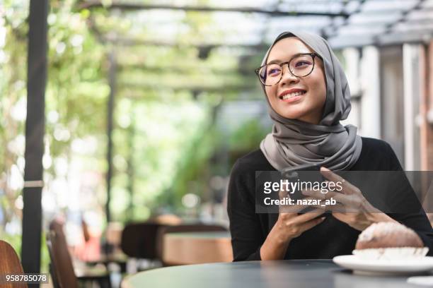 malaysische ambitionierte geschäftsfrau mit smartphone in der hand. - indonesian ethnicity stock-fotos und bilder