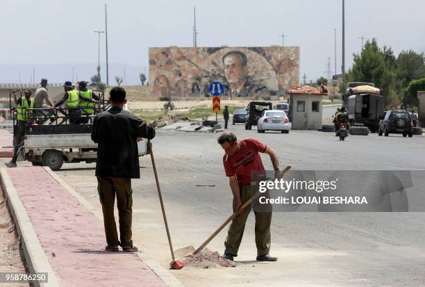 Workers repair a pothole on the highway extending from Harasta in Eastern Ghouta on the outskirts of Damascus to the northern part of Syria, after it...