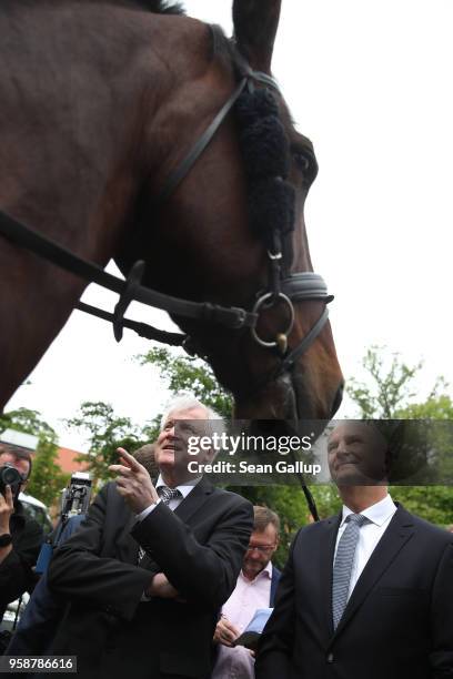 German Interior Minister Horst Seehofer and Brandenburg state Governor Dietmar Woidke chat with mounted police officers during a visit to the German...