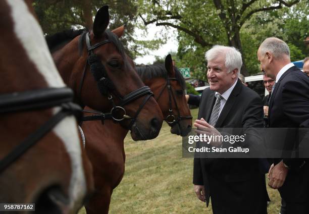 German Interior Minister Horst Seehofer and Brandenburg state Governor Dietmar Woidke chat with mounted police officers during a visit to the German...