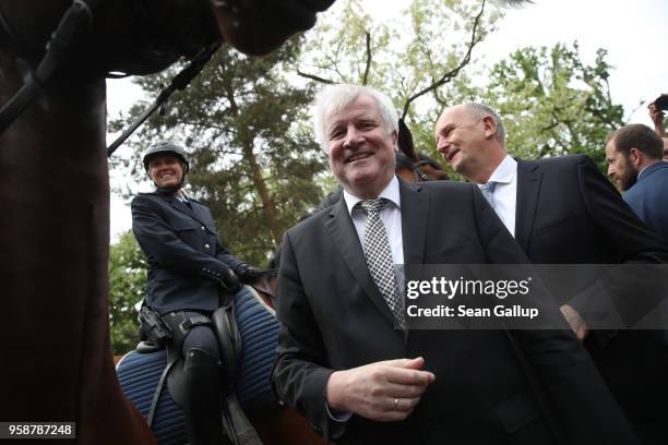 German Interior Minister Horst Seehofer and Brandenburg state Governor Dietmar Woidke chat with mounted police officers during a visit to the German...