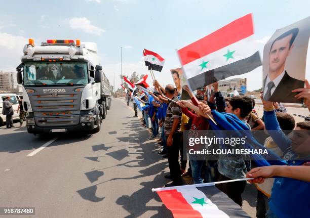 Children wave national flags and carry portraits of Syrian president Bachar al-Assad on the highway extending from Harasta in Eastern Ghouta on the...
