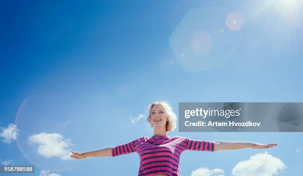 smiling girl doing exercises on sky background - spread joy stock pictures, royalty-free photos & images