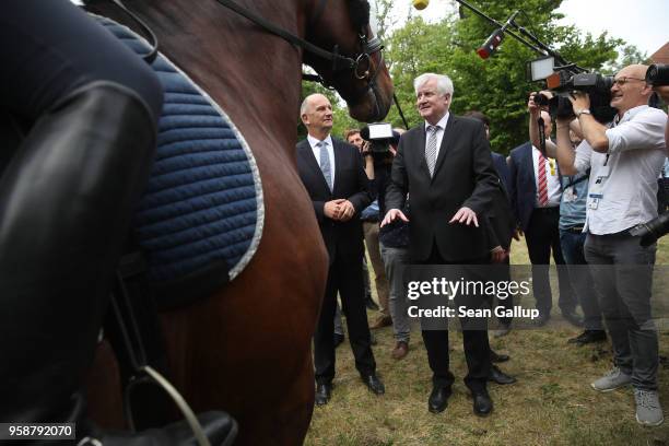 German Interior Minister Horst Seehofer and Brandenburg state Governor Dietmar Woidke chat with mounted police officers during a visit to the German...