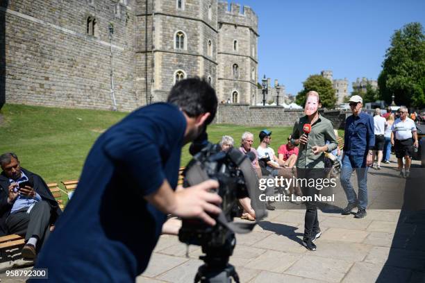 Television reporter wears a Prince Harry mask during a peice to camera, as fans begin to arrive ahead of a four day wait for the royal wedding of...