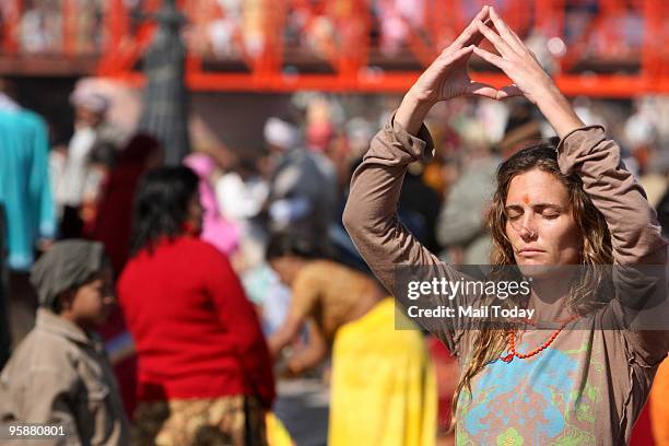 Foreigner devotee prays as she takes holy dip in the river Ganges on the auspicious occasion of Mauni Amavasya during the Maha Kumbh in Haridwar on...