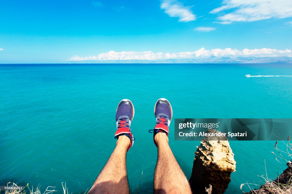 Personal perspective of man's feet against blue sea and sky