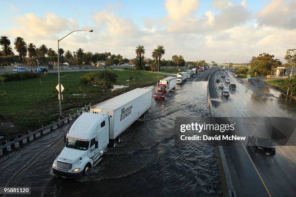 Trucks move through flood waters in southbound lanes of the 710 freeway as the freeway is shut down during the evening rush hour after the second...