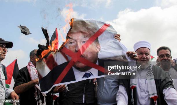 Protesters including Lebanese nationals and Palestinian refugees living in Lebanon burn a large print of US President Donald Trump during a...