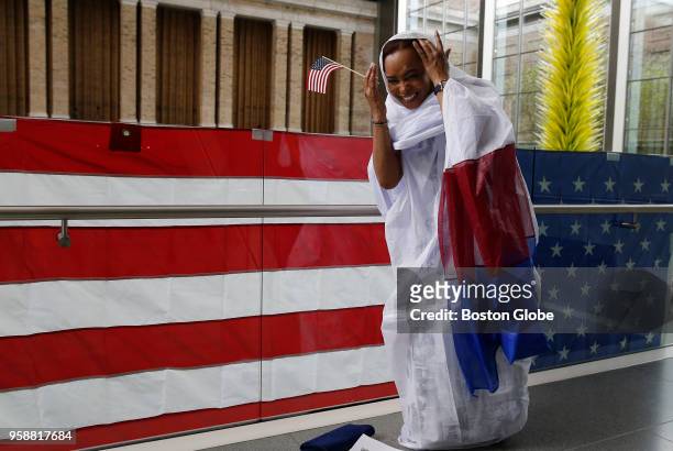 Lemina Cisse, who is originally from Mauritania, laughs as she fixes her head covering after posing for a picture behind an American flag shortly...
