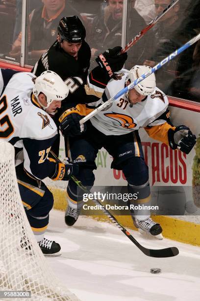 Sheldon Brookbank of the Anaheim Ducks battles for the puck behind the net against Adam Mair and Matt Ellis of the Buffalo Sabres during the game on...