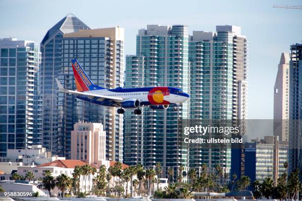 Boeing 737 of Southwest Airlines approaching Lindbergh Field, with high rises of the San Diego skyline in the background.