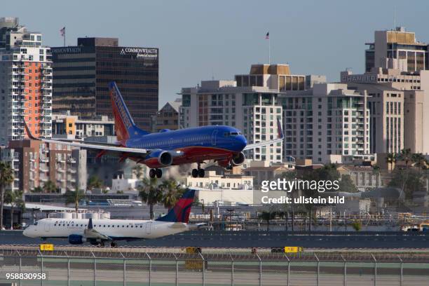 Boeing 737 of Southwest Airlines approaching Lindbergh Field, with high rises of the San Diego skyline in the background.