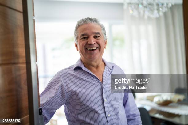 mature man welcoming home opening his front door - door greeting stock pictures, royalty-free photos & images