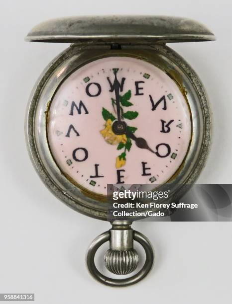 Silver-colored, pro-suffrage pocket watch or fob watch, with the phrase "Vote for Women, ” with each letter corresponding to a numeric position, and...