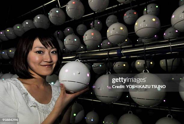 An employee of Japanese weather forecasting company Weathernews displays some of the 700 pod-shaped pollen counting robots called "Pollen-robot",...