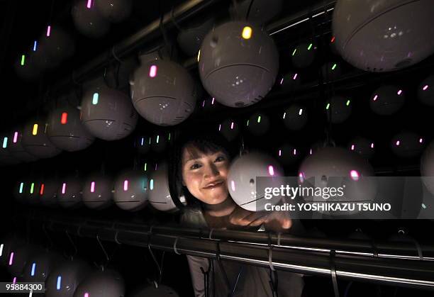 An employee of Japanese weather forecasting company Weathernews displays some of the 700 pod-shaped pollen counting robots which are ready to be...