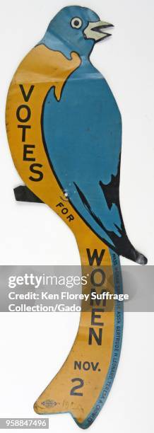 Blue and orange tin bird, with the text "Votes For Women Nov 2, " intended to be used as campaign ephemera, nailed on fence posts, telephone poles,...