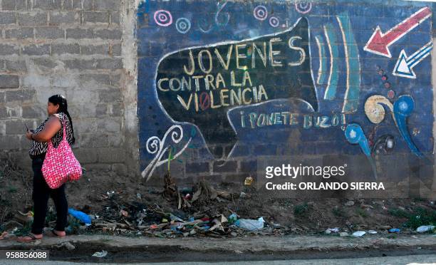 Woman stands next to a graffiti reading "Youths Against Violence" in the poor neighbourhood of Nueva Capital, on the outskirts of Tegucigalpa, on May...