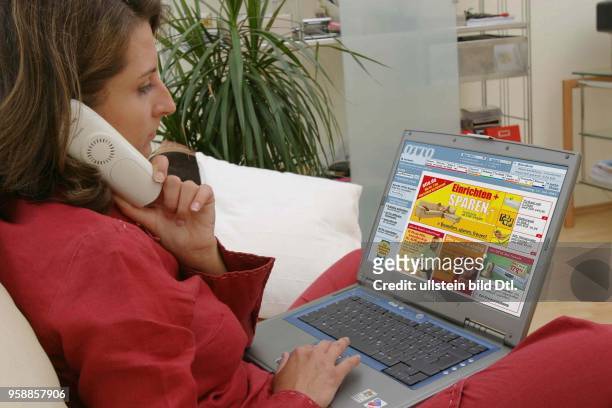 Deutschland, Internethandel, Online-Shopping, Frau sitzt zuhause auf dem Sofa und surft mit Notebook im Internet auf der Seite des Versandhauses Otto...