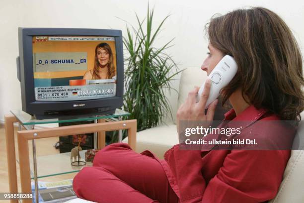 Fernsehen, Gewinnspiele, Frau telefoniert und schaut eine Gewinnspiel