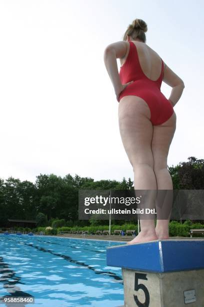 Junge Frau im Badeanzug steht auf einem Startblock am Beckenrand im Poseidon-Freibad