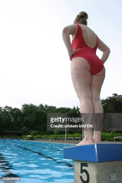 Junge Frau im Badeanzug steht auf einem Startblock am Beckenrand im Poseidon-Freibad