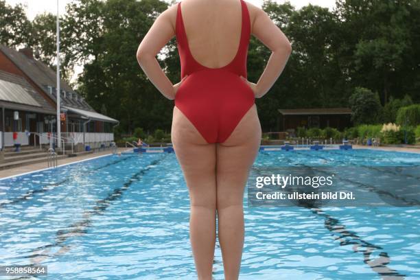 Junge Frau im Badeanzug steht auf einem Startblock am Beckenrand im Poseidon-Freibad