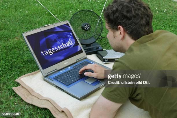 Fernsehen, digitales Fernsehen DVB-T, Mann liegt auf der Wiese und guckt auf seinem Laptop Fernsehen -