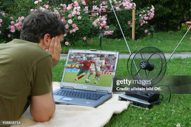 Fernsehen, digitales Fernsehen DVB-T, Mann liegt auf der Wiese und guckt auf seinem Laptop Fernsehen -