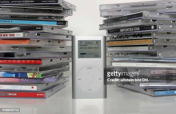 Player iPod mini von Apple zwischen zwei Stapeln CDs