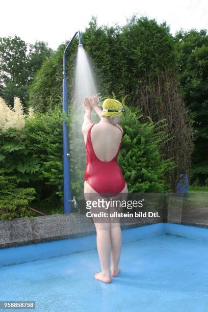 Junge Frau im Badeanzug unter der Dusche im Poseidon-Freibad