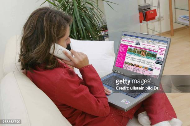 Deutschland, Internethandel, Online-Shopping, Frau sitzt zuhause auf dem Sofa und surft mit Notebook im Internet auf der Seite eines Last-Minute...
