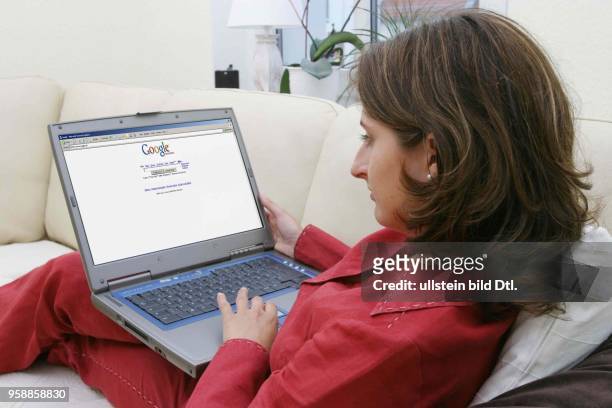 Deutschland, Internethandel, Online-Shopping, Frau sitzt zuhause auf dem Sofa und surft mit Notebook im Internet auf der Seite der Suchmaschine...