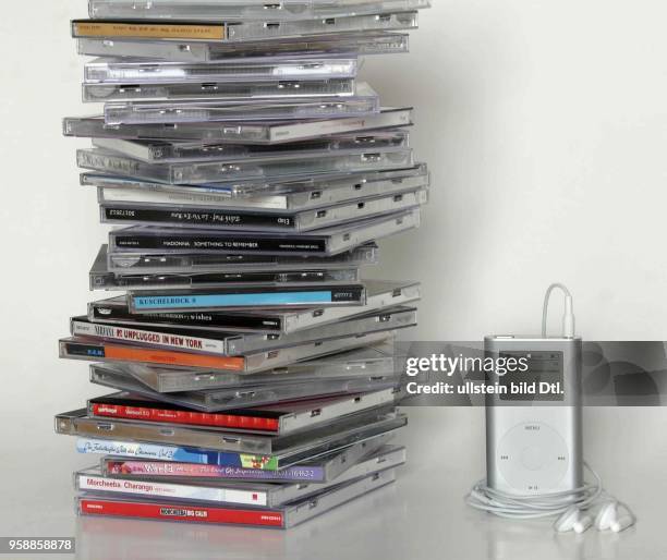 Ein iPod mini von Apple steht neben einem Stapel CDs.