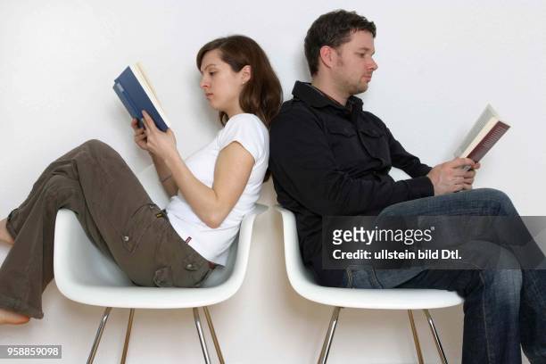 Deutschland, Mann und Frau sitzen Rücken an Rücken und lesen ein Buch