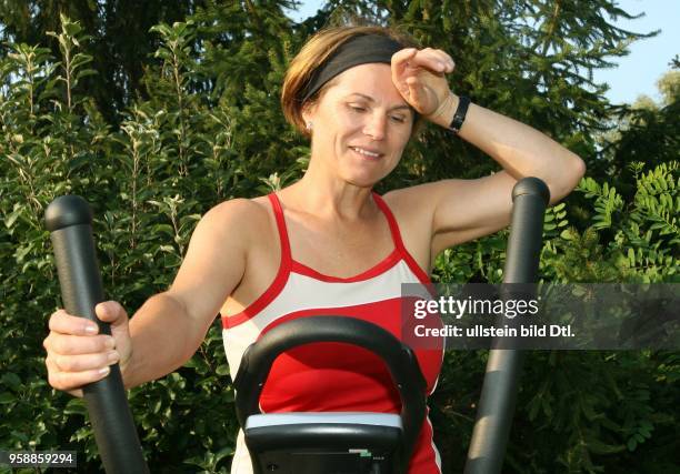 Yoga, woman on a crosstrainer in the garden and is exhausted -