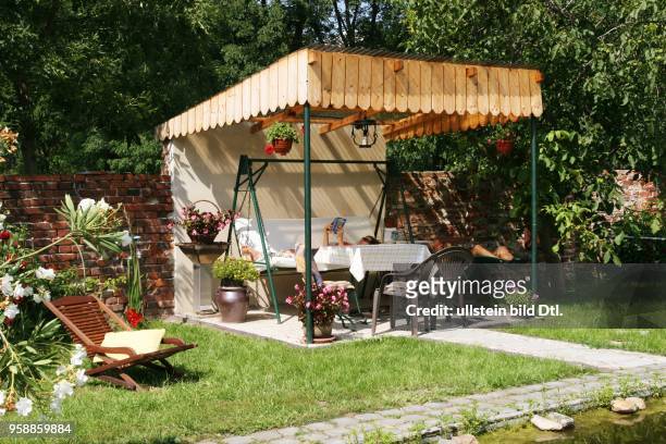 Germany - Brandenburg - Altlewin: woman is relaxing on a Framed Hammock in the garden of a farm -