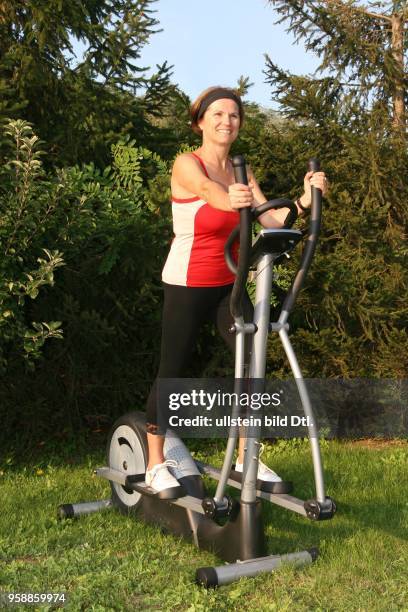 Yoga, woman on a crosstrainer in the garden -