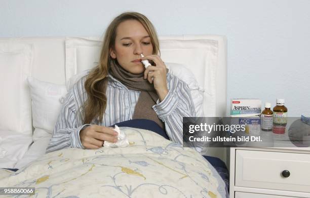 Ill woman laying in the bed with nasal spray